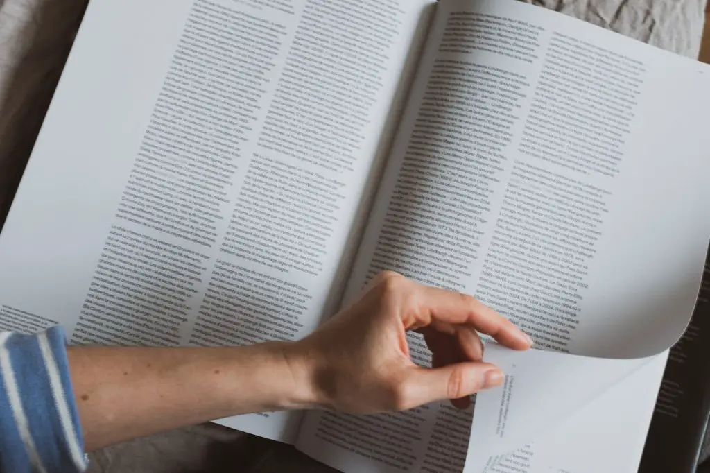 person paging a book in bed